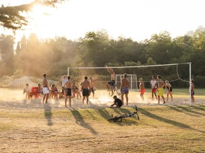 Junge Leute spielen Beachvolleyball bei Sonnenuntergang.