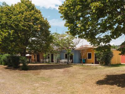 Maisons colorées parmi les arbres, avec des chaises blanches à l'extérieur.