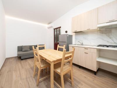 Modern kitchen with wooden table and grey sofa.