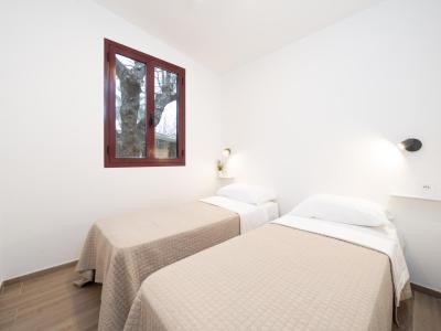 Room with two single beds, window, and white walls.