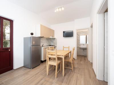 Modern kitchen with wooden table and bathroom in the background.