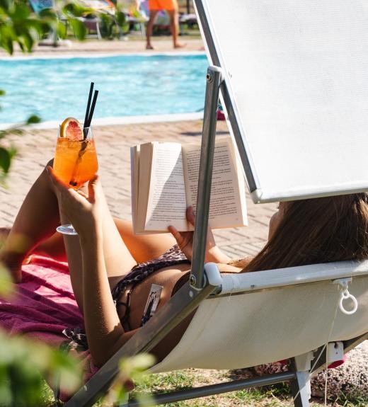 Détente au bord de la piscine : lecture et cocktail sous le soleil d'été.
