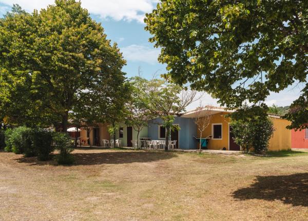 Maisons colorées parmi les arbres, avec des chaises blanches à l'extérieur.
