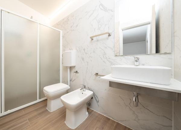 Modern bathroom with shower, sink, bidet, and toilet.