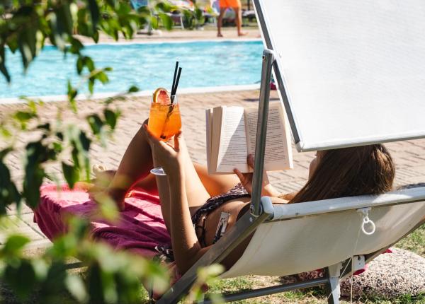Entspannung am Pool: Lesen und Cocktail unter der Sommersonne.