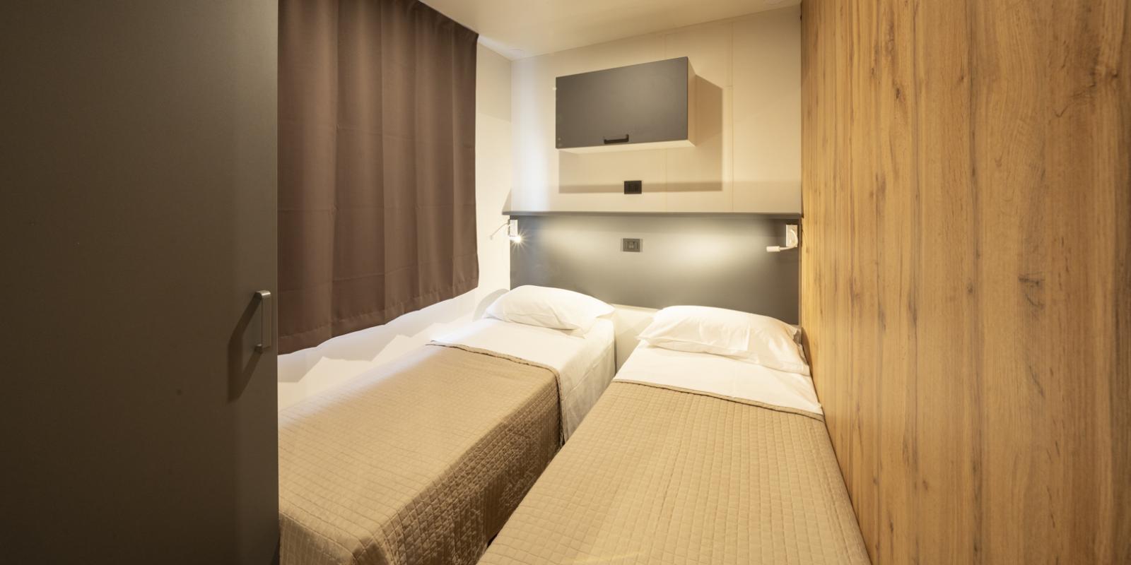 Chambre minimaliste avec deux lits simples et mur en bois.