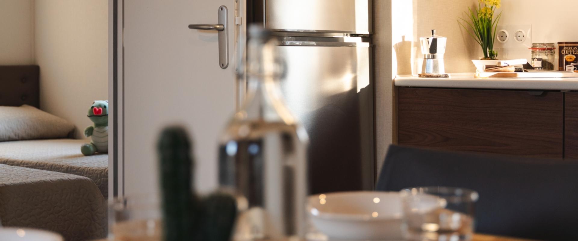 Cucina moderna con frigorifero e macchina da caffè, vista su camera con peluche.