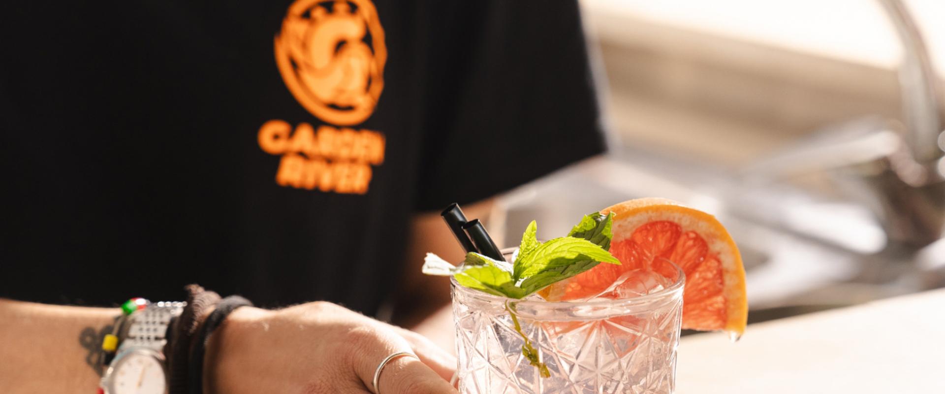 Un drink rinfrescante con menta e pompelmo, servito da un cameriere con orologio e bracciali.