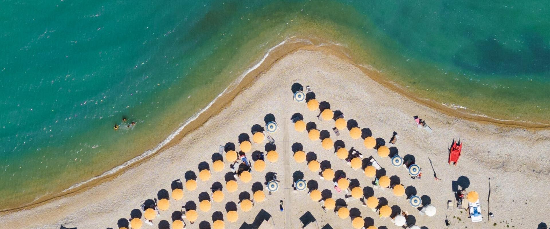 Vista dall'alto di una spiaggia con ombrelloni gialli e mare cristallino.