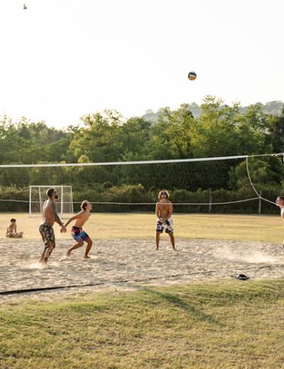 Vista aerea di un campo da pallavolo con persone che giocano sulla sabbia.