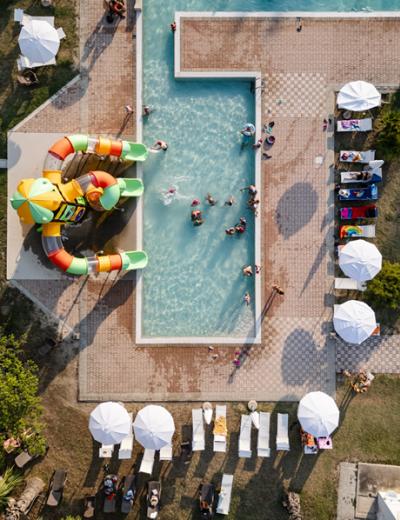 Donna legge un libro e beve un cocktail a bordo piscina su una sdraio.