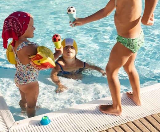 Bambini che giocano in piscina con giocattoli a forma di pallone da calcio.