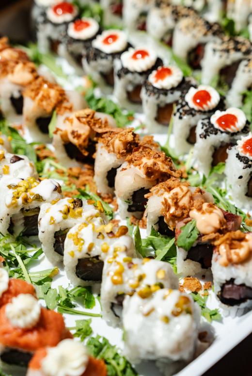 Colorato sushi gourmet con salse, erbe fresche e decorazioni croccanti.