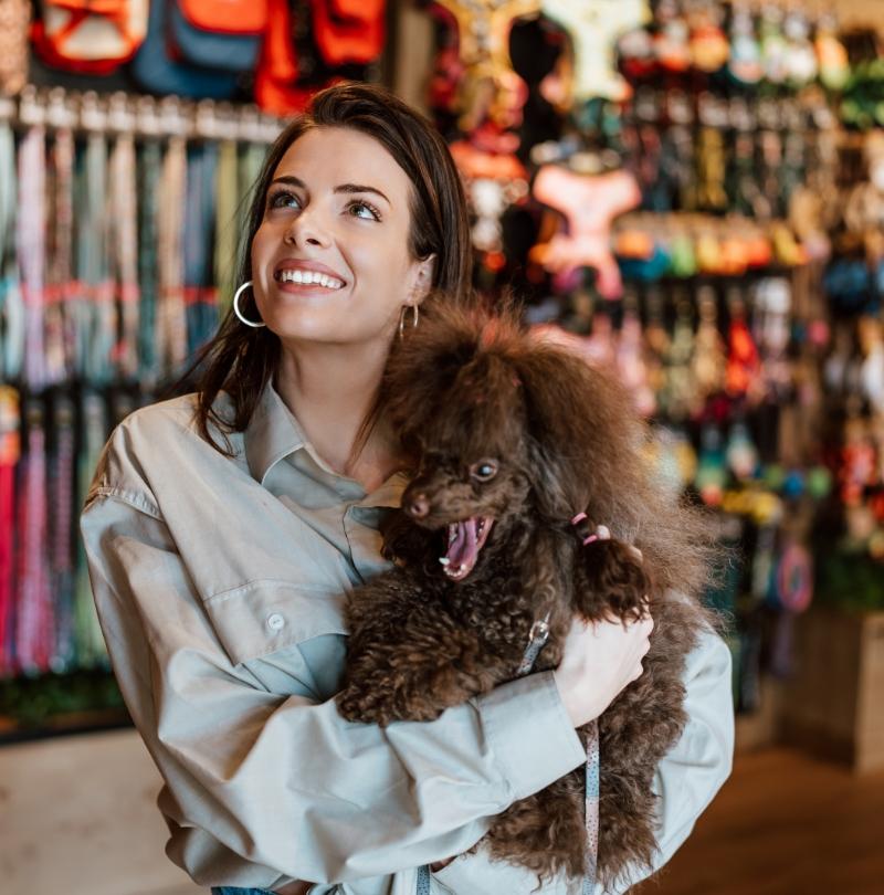 Donna sorridente con cane in negozio di articoli per animali.